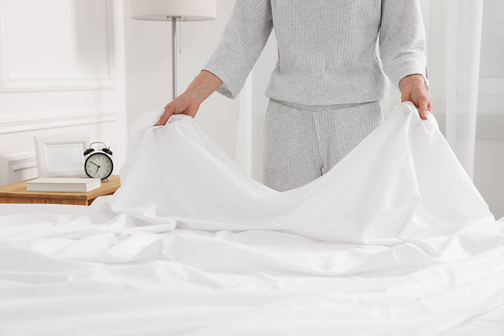 Bedwetting Treatment — person changing wet bed sheets in the morning.