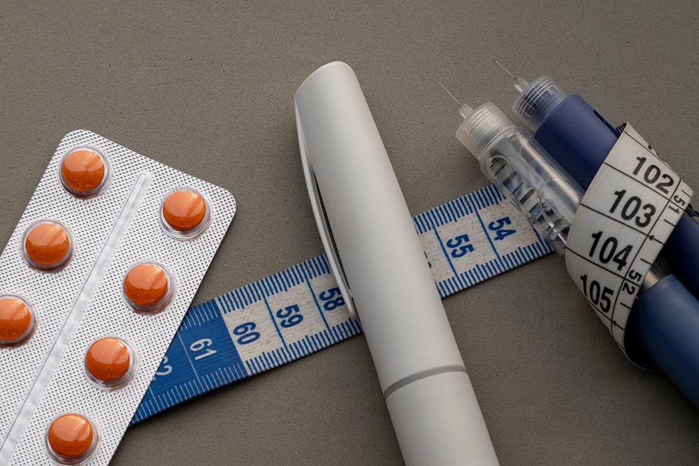 Overweight and Obesity Treatment — weight-loss pills, GLP-1 injection pens and a measuring tape.